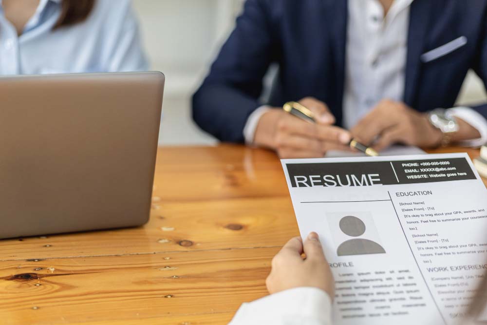 HR Associate from a manpower service provider company is interviewing two applicants while holding their resumes