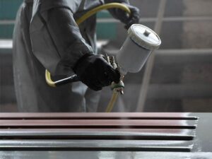 worker is using spray paint to paint the metal