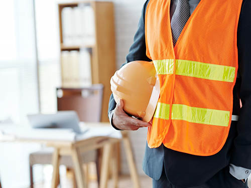 man from a company that offer construction services is wearing a safety vest and holding a hard hat