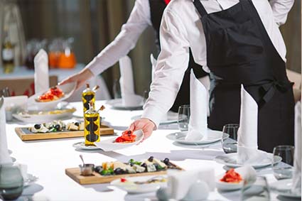 waiter is setting up the food on the table