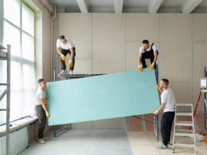 property management team assisting each other in lifting a rectangular plywood sheet