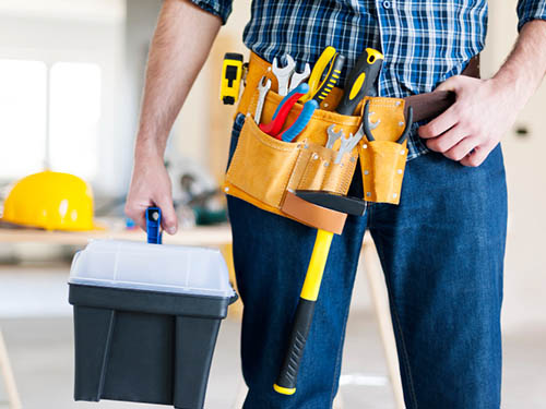 property maintenance worker with tools on his belt and additional tools in his right hand