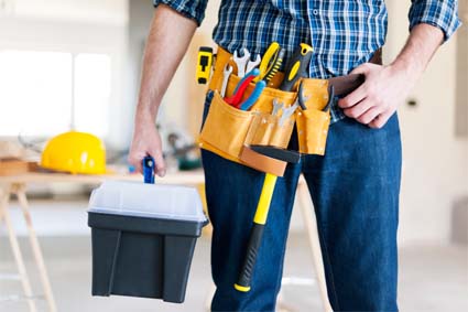 property maintenance worker with tools on his belt and additional tools in his right hand