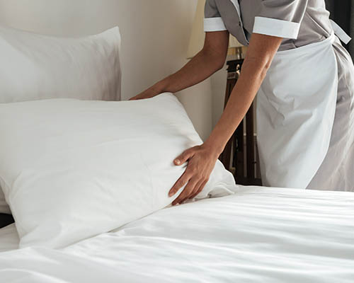 professional housekeeper arranging the pillows and making the bed