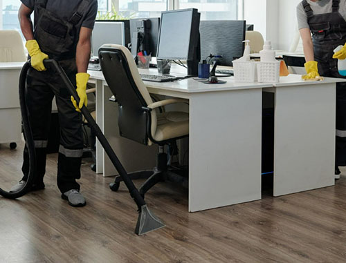two worker cleaning the floor with a vacuum and wiping the table