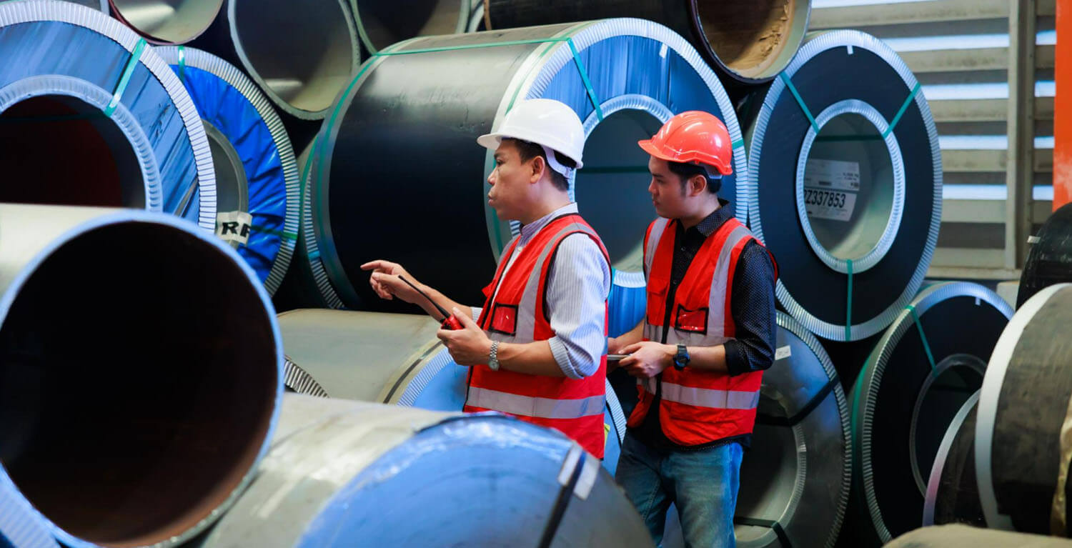 warehouse worker conducting an inspection of large pipes alongside their trainee